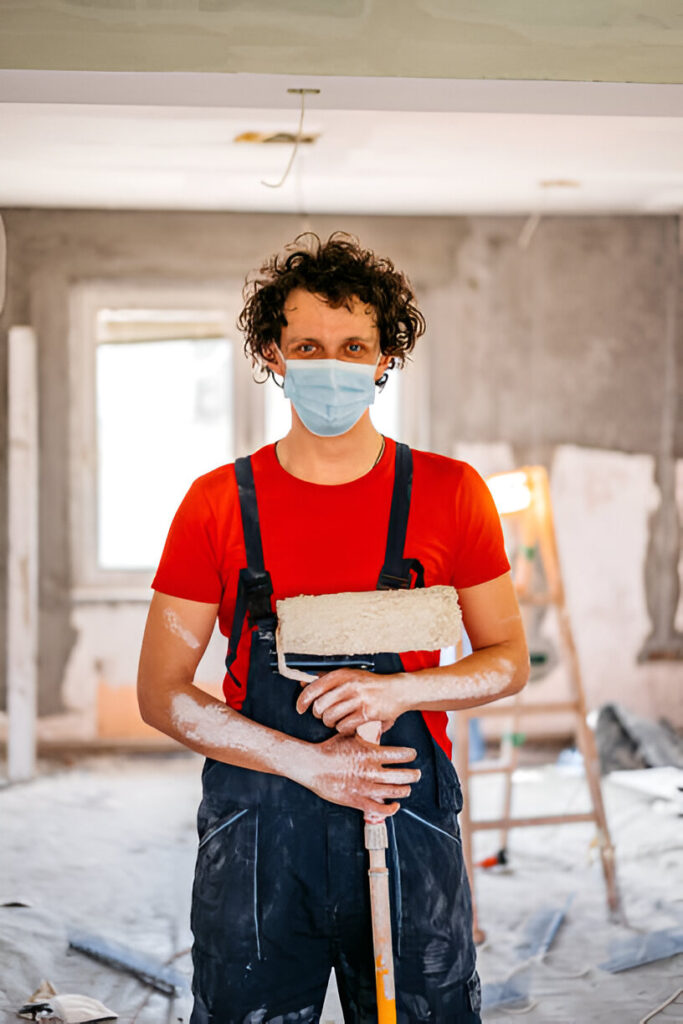 A man is holding brush and roller for the painting