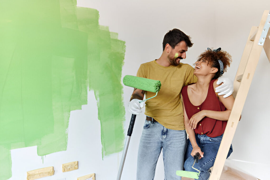 Young happy couple communicating on a break from painting their walls during home renovation process. Copy space.