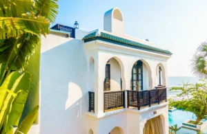 A beautifully painted white coastal villa with green roof tiles. A classic result of expert Villa Painting Dubai techniques designed to withstand humidity and sea breeze.
