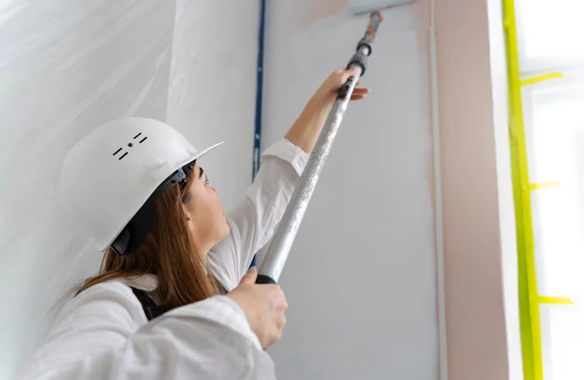 A skilled painter applies a fresh coat of paint to an apartment interior wall, showcasing the precision and quality delivered by top apartment painting Dubai services.