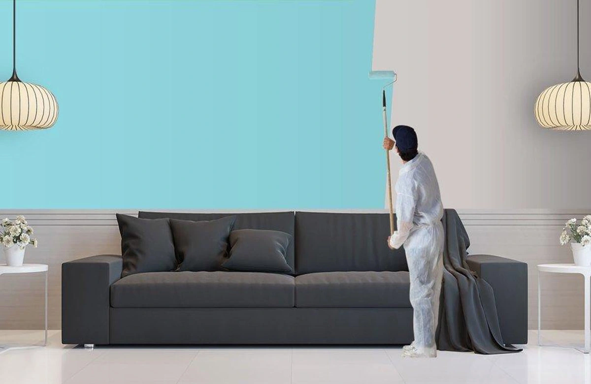 Man painting a wall sky blue in a modern living room.