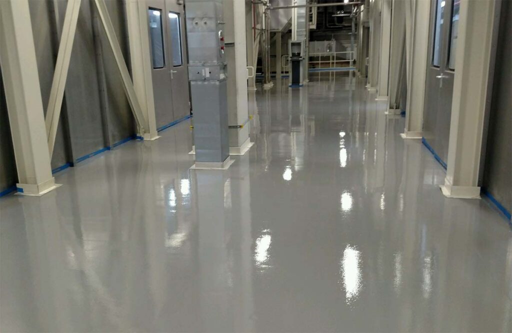 Shiny epoxy-coated factory floor completed by industrial painting services in Dubai for durability and cleanliness.